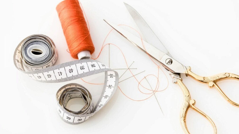 measuring tape, needle, orange thread, scissors