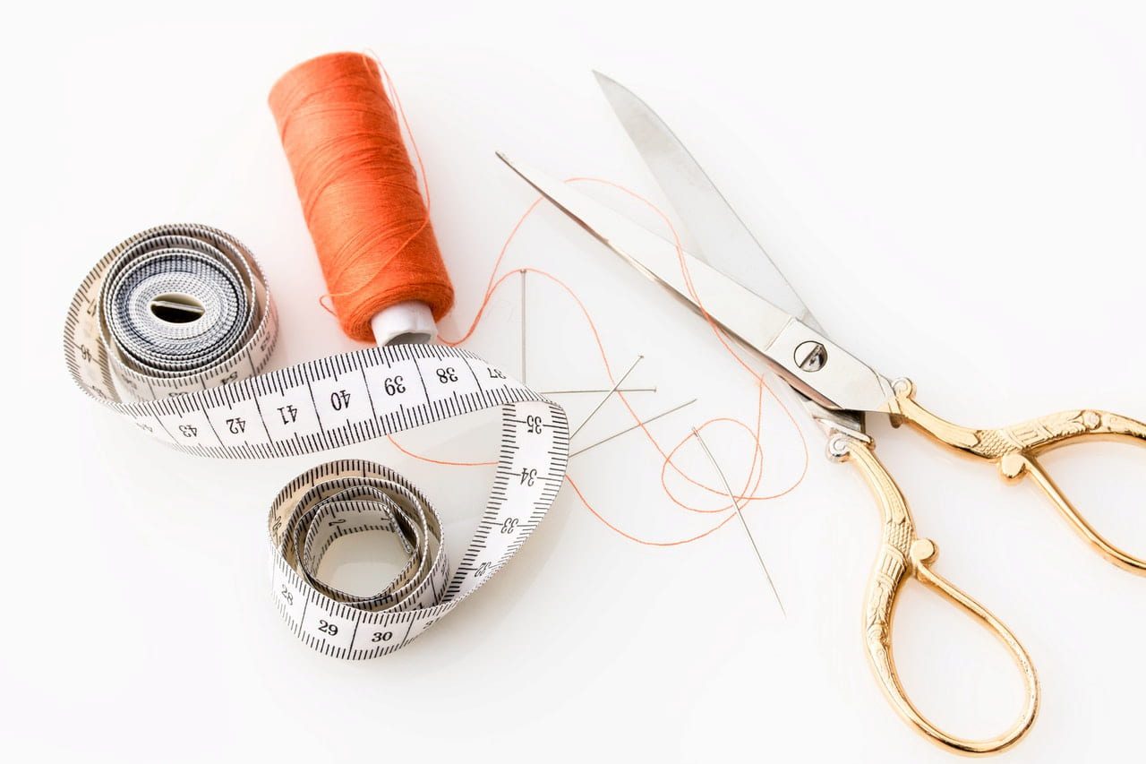 measuring tape, needle, orange thread, scissors