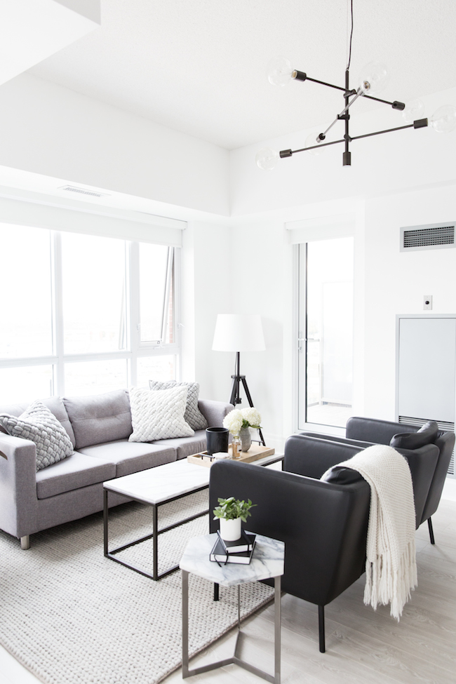 Monochromatic living room with grey sofas and black armchairs