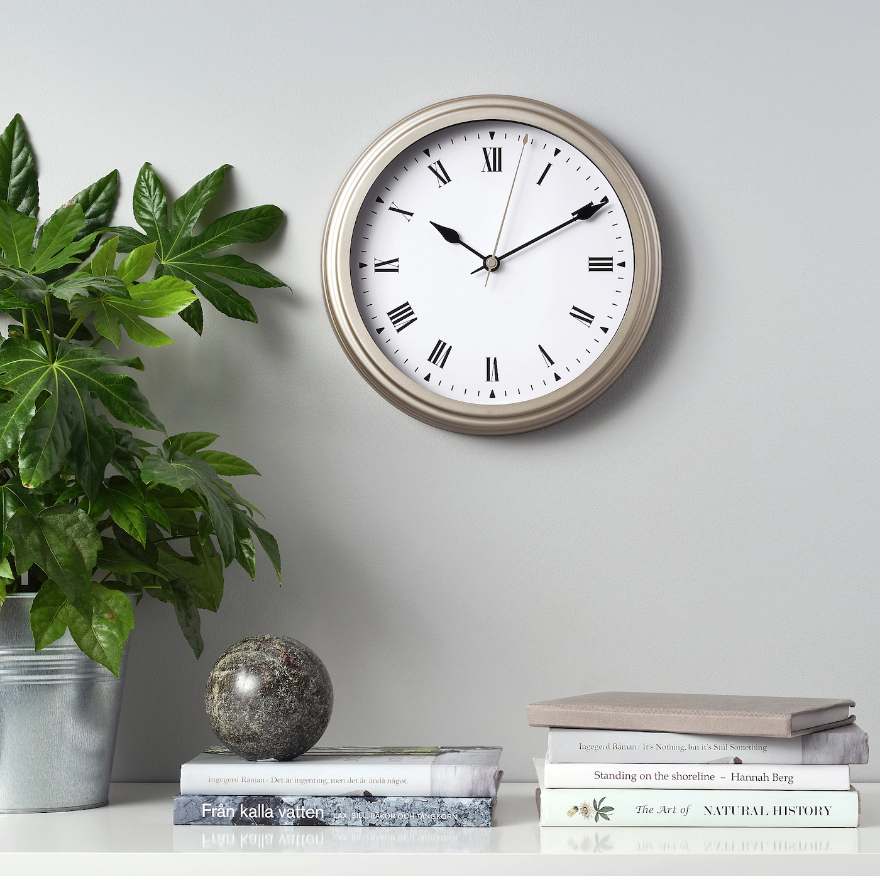 Books with plants on a table and IKEA Vischan beige wall clock