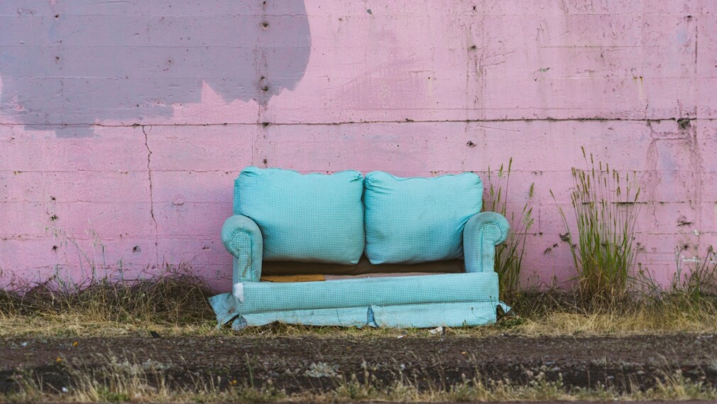 old blue sofa against pink wall